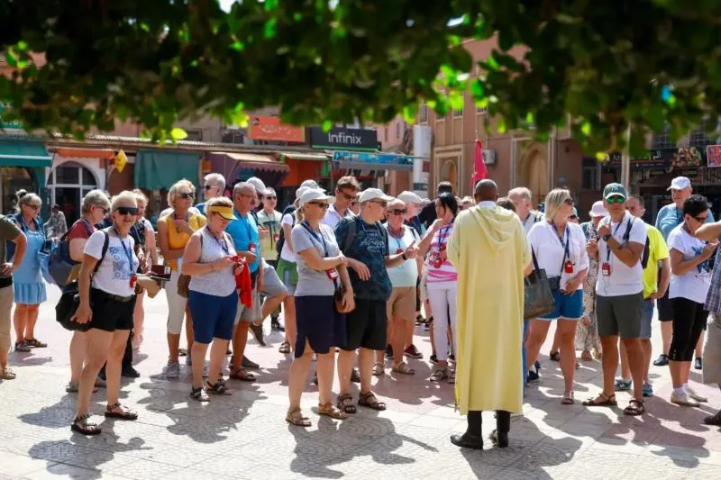 Group of travelers following their guide through the Marrakech medina on 6 Day Morocco Express Tour