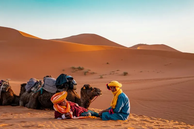 Berber camel guide resting with his camel on the Erg Chebbi dunes near Merzouga