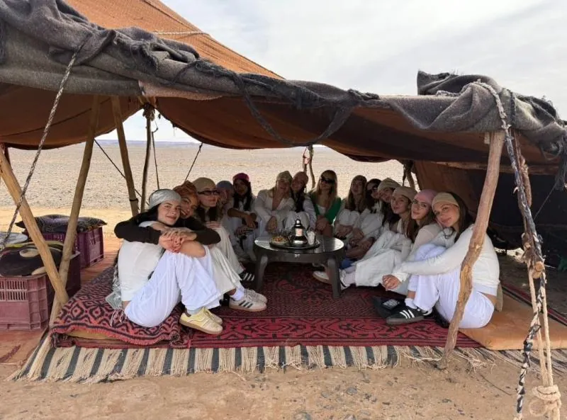 Travelers sharing tea with a nomad family in their tent on 12 Days Tour from Marrakech