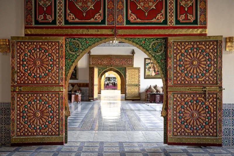 Carved wooden doors opening onto a traditional Moroccan courtyard